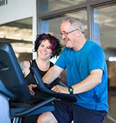 YMCA staff helping new member use cardio equipment