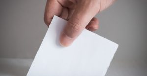 hand placing ballot in box