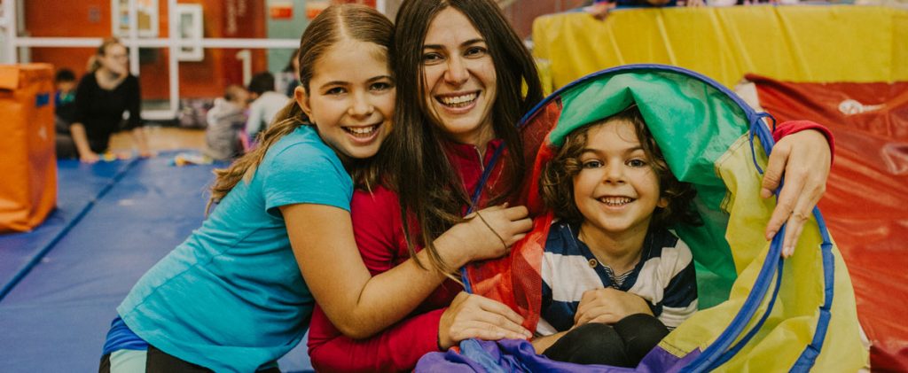 Mom and two children smiling in YMCA gymnasium