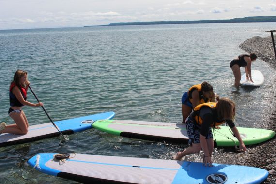 boys and girls learning how to stand up paddle board at Camp Presqu'ile